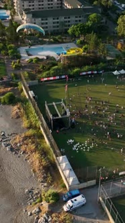 Aerial View: People Gather on Field Near Beach