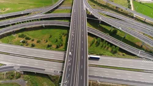 Expansive aerial view of highway junction with overpasses and curved roads in countryside setting