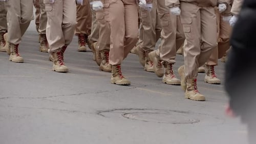 Groundlevel View of Uniformed Personnel Marching in Formation on a Street Combat Boots and Khaki