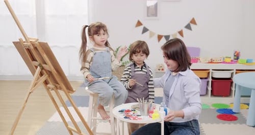 Children and Adult Painting in a Classroom