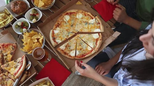 Close-up of young people taking slice of pizza from the box
