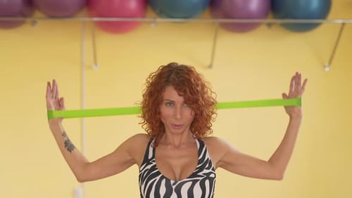 Close shoot of curly red haired woman with tattoo on hand. She is in sport hall and wears zebra spor