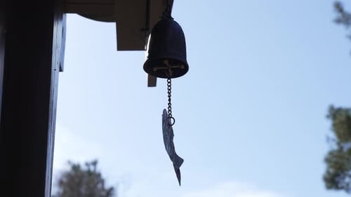 Traditional Buddhist Wind Chime Swaying Gently Under a Bright Blue Sky