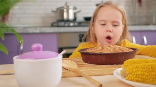 Girl Looks at Cake on Kitchen Table