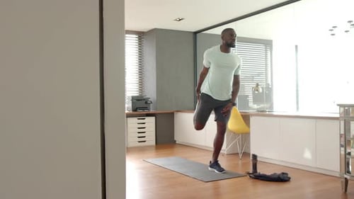 Stretching on yoga mat, fit man exercising in modern home office setting