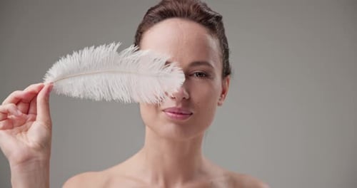 Woman Posing with a White Feather in Studio