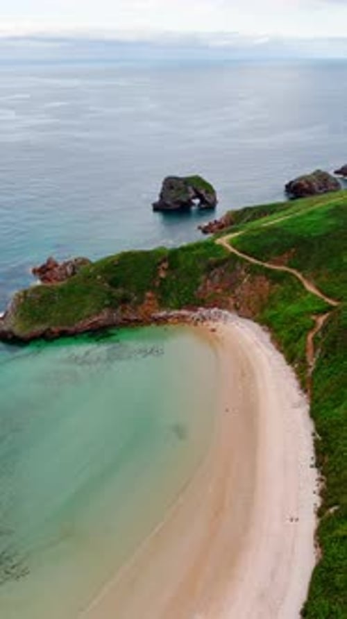 Flug über den exotischen Sandstrand, umgeben von Felsen.