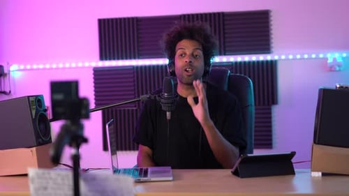 Streamer recording a podcast using microphone and laptop sitting on a studio