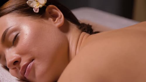 Une belle jeune femme bénéficie d'un massage relaxant aux pierres chaudes dans un spa de luxe