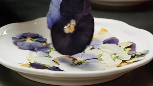 Edible Flowers Being Placed on Plate with Tongs