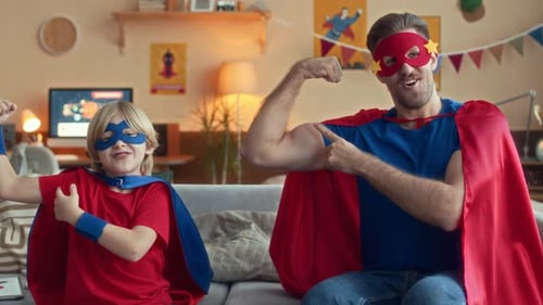 Father and Son Dressed as Superheroes Flexing