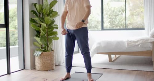 Man Stretching Arms on Yoga Mat in Bedroom