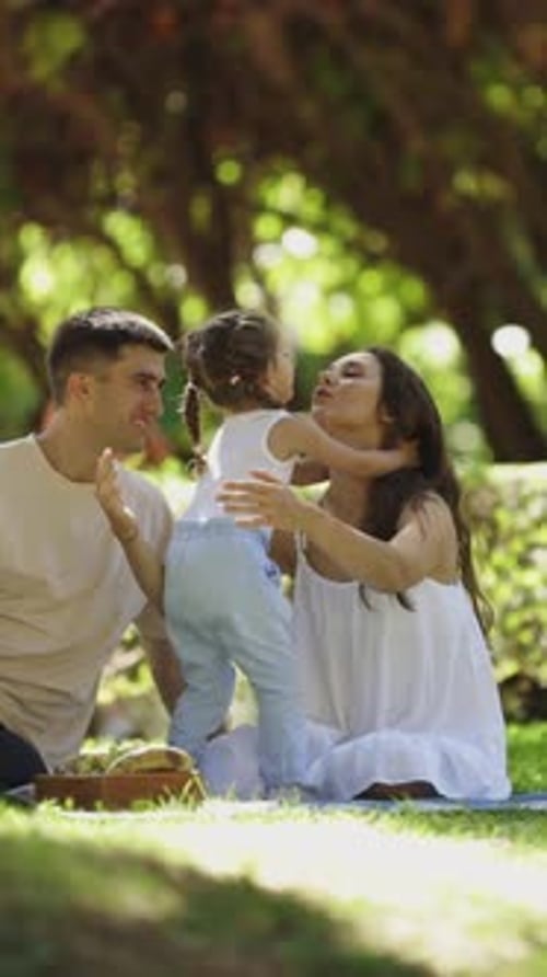 Happy Family Enjoying Picnic in Shaded Grassy Park
