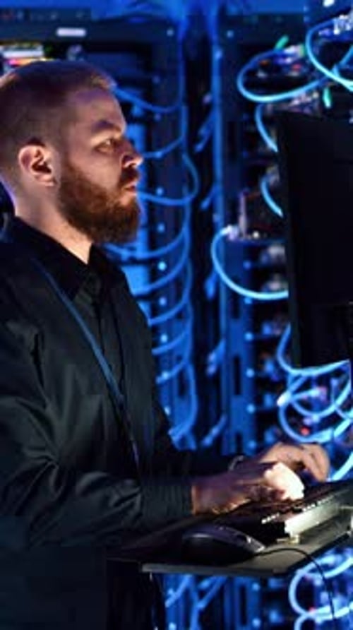 Man Working in Dark Server Room with Computers