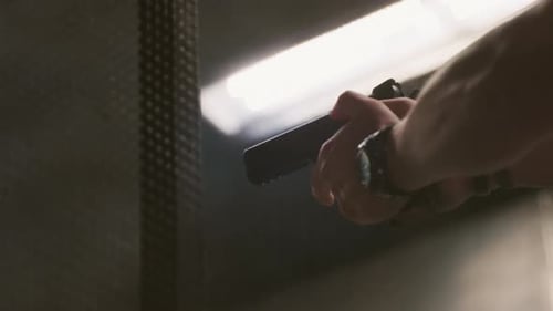 Hände der Männer feuern eine Feuerwaffe ab Die Waffe befindet sich im Schießstand, die Patronenhülle fliegt heraus