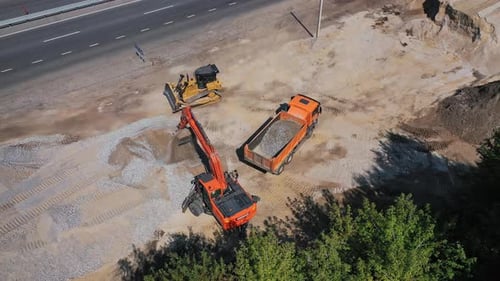 Excavator pours sand into the truck. Aerial view of excavator with truck working in quarries site