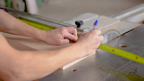 Unrecognizable Carpenter Sawing Wooden Plank in Workshop