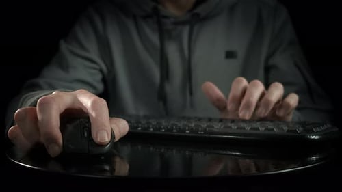 Person Using Keyboard and Mouse in Dark Setting