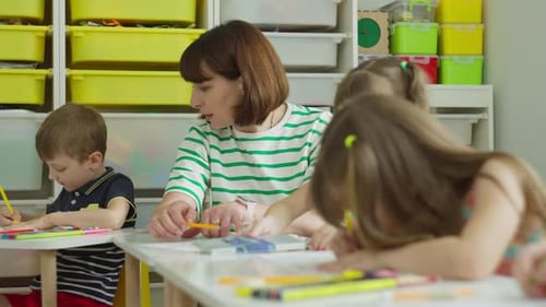 Teacher Helping Children with Drawing in Classroom