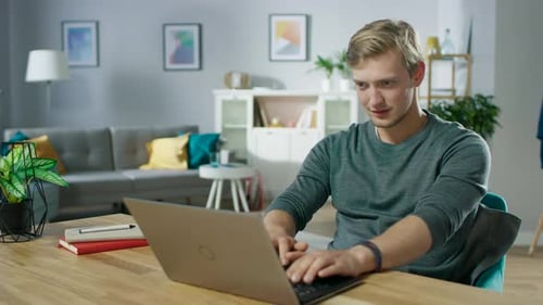 Man Working on Laptop at Wooden Desk Indoors