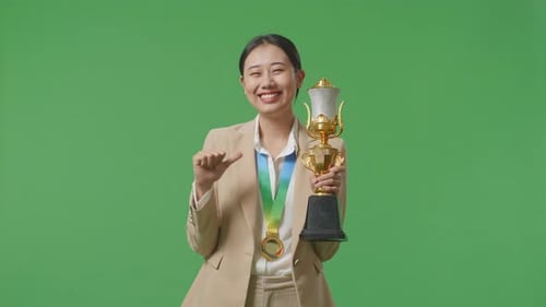 Geschäftsfrau zeigt Goldtrophäe vor die Kamera und zeigt, dass sie stolz auf dem grünen Bildschirm ist