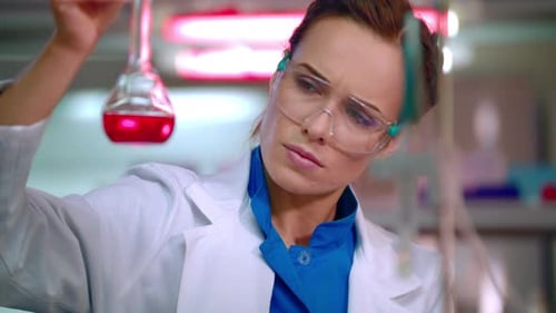 Focused Woman Scientist Analyzes Red Liquid in Laboratory