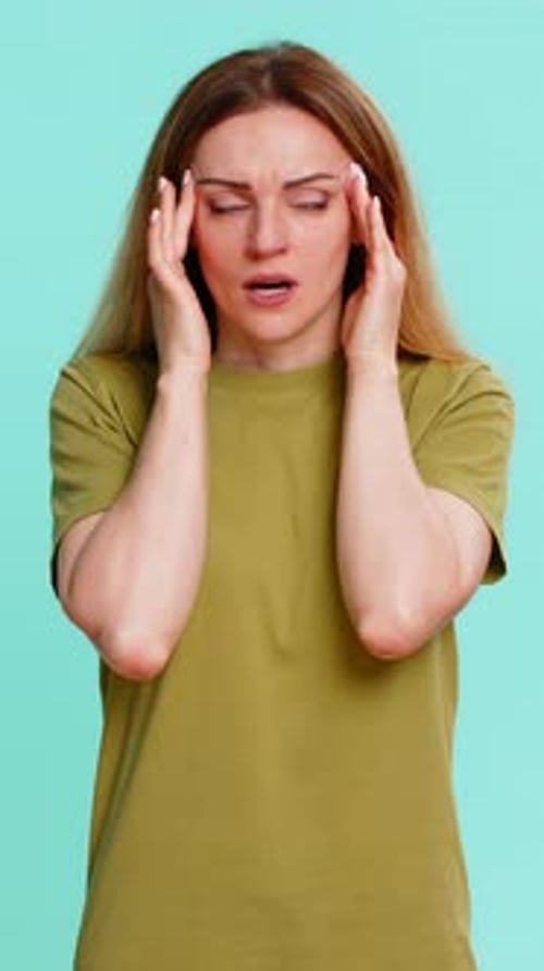 Woman Rubbing Temples with Headache Against Light Blue Background
