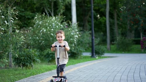 Beautiful smiling baby riding his scooter approaching camera.