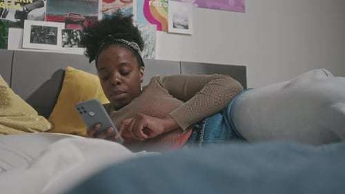 Young Black Woman Browsing on Smartphone in Bed