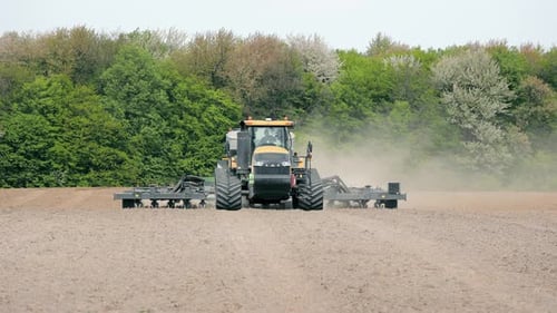 Tractor Preparing Field for Planting A Large Tractor Equipped with Farming Machinery Plowing a Vast