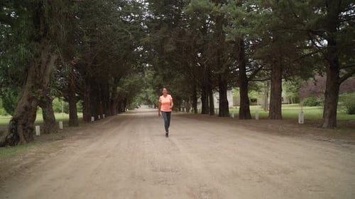 The Lady is Walking Briskly in the Park - Wide Shot