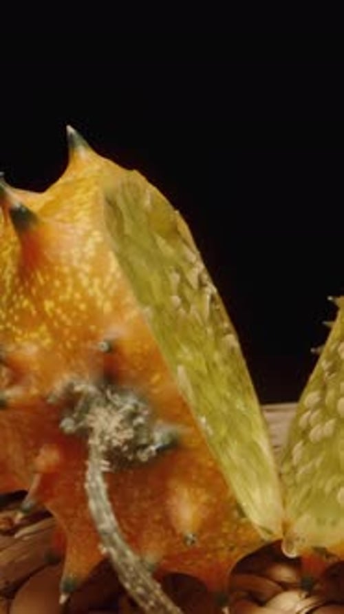 Vidéo verticale. Trois concombres oranges Kiwano aux pointes acérées sont placés sur une table
, avec des dimensions variables