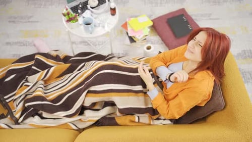 Woman Lies On Couch Feeling Ill Under Blanket