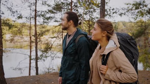 Engaged Pair Walking Along Lake in Coniferous Forest