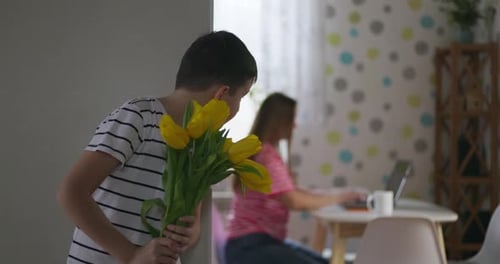 Child Gives Yellow Flowers to Woman Indoors
