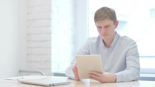 Frustrated Young Man Using Tablet in Office