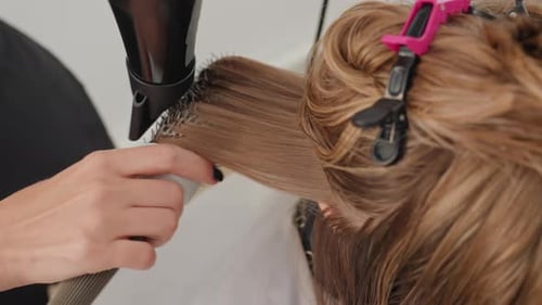 Hairstylist Drying and Styling Hair in Salon Close-up