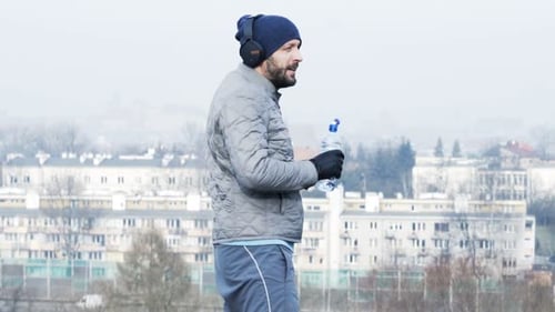 Young Male Jogger Finish Jogging and Drinking Water in City Park Active