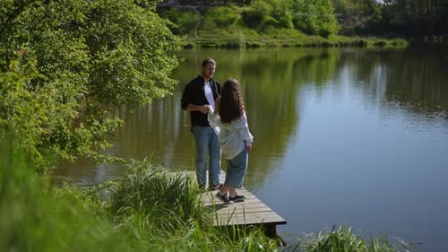 Couple Embracing on Dock by Calm Lake