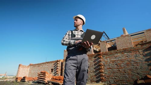 Construction Foreman Reviewing Plans on Laptop