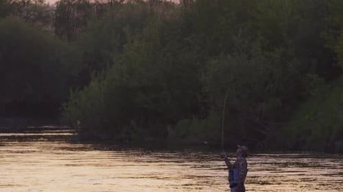 Fly fishing. Fisherman casts fly on the river at sunset. Caucasian amateur angler fishing
