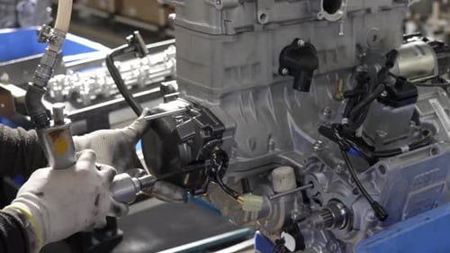 Gros plan d'un ouvrier d'une chaîne de montage utilisant un tournevis pneumatique pour fixer un couvercle sur un