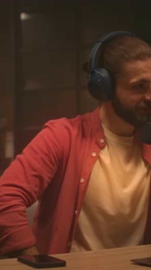 Host Smiles Microphone Gentleman in Casual Attire Recording Music or Speech During Cozy Late Night