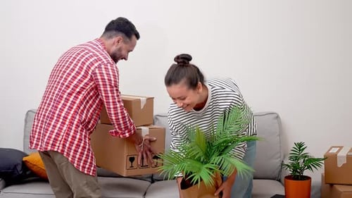 Couple Relocating Internationally in New Living Room with Cardboard Relocation Service Boxes