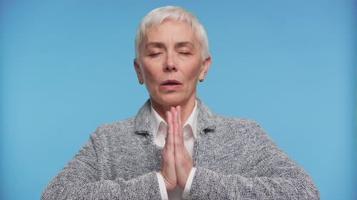 Peaceful Mature Woman Meditating on Blue Background