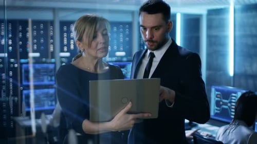 In System Control Room Female and Male Top Managers Have Discussion. In the Background Professional