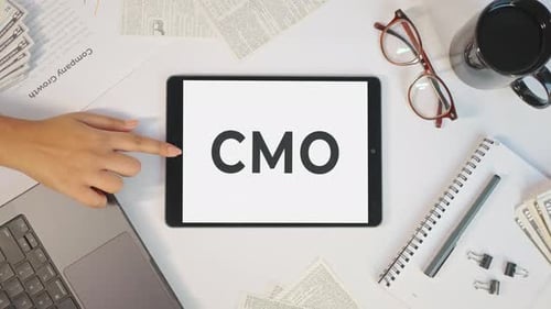 Hand Tapping Tablet Displaying CMO on Desk