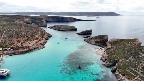 Un Drone survole le Blue Lagoon entre les eaux turquoises du récif de Comino et Cominotto Malta