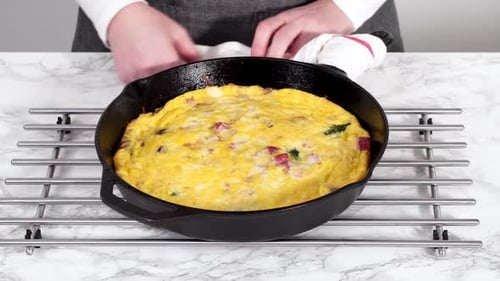 Frittata aux épinards et au jambon fraîchement cuite dans une poêle en fonte