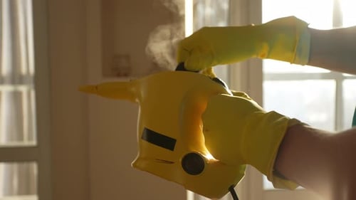 Closeup Side View of Unrecognizable Wearing Protective Rubber Gloves Checking Out Steam Cleaner